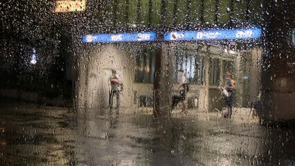 車窓から見た雨の日の駅の入り口で帰宅する人々の姿