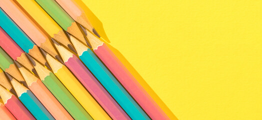 Colored wooden pencils on yellow background. Top view with copy space. Flat lay. Back to school concept.