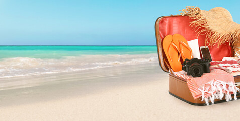 Open suitcase on sea beach. Travel concept