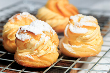 Choux cream, delicious pastries sprinkled with icing.