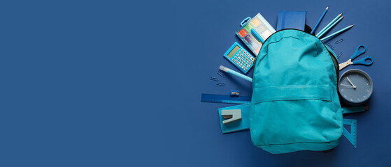 School backpack and stationery on blue background with space for text