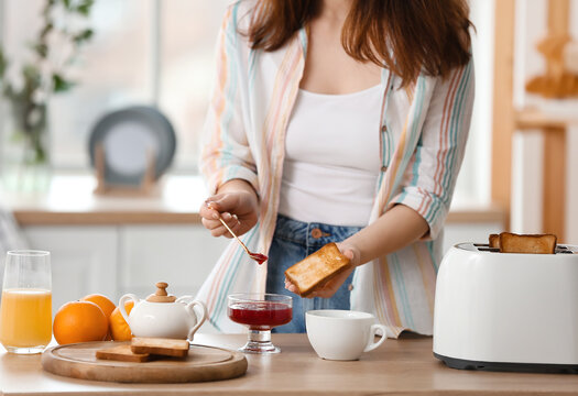 Beautiful young woman making tasty toasts in kitchen - Powered by Adobe