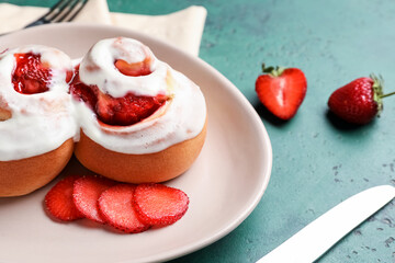 Plate with strawberry cinnamon rolls on green background, closeup