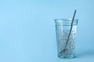 Glass of water with chia seeds on blue background