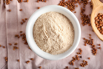 Bowl of buckwheat flour on pink fabric background, closeup
