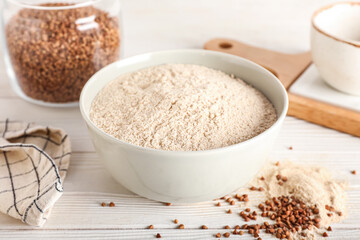 Bowl of buckwheat flour on white wooden background, closeup