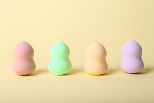 Row of different makeup sponges on color background