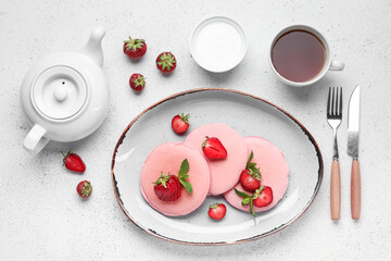 Composition with plate of tasty pancakes, strawberry, sour cream and tea on light background