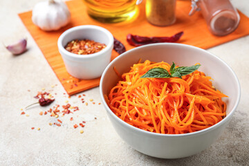 Bowl of tasty korean carrot salad on light background