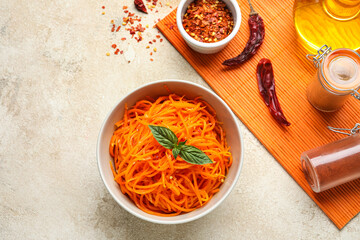 Composition with bowl of korean carrot salad and ingredients on light background