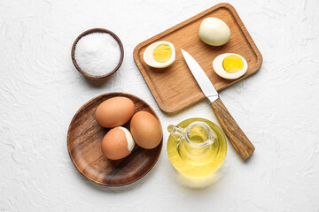 Composition with boiled chicken eggs, salt and oil on light background