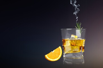 Whiskey or cognac in cristal glass with smoked rosemary, and slice of orange. Alcoholic drink.
