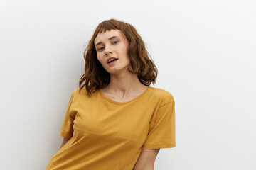 Obraz premium a sweet, beautiful, romantic woman in a yellow T-shirt poses on a white background, smiling pleasantly looking at the camera. Horizontal photo with an empty space for inserting an advertising layout