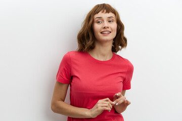 a beautiful, sweet, modest woman with red hair stands on a white background in a red T-shirt and...