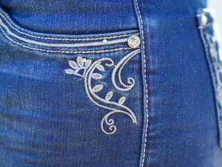Closeup of blue jeans with white stitching and embroidered detail
