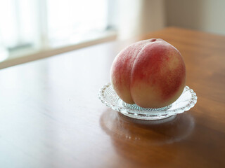 透明のガラスのお皿に乗せた桃
