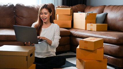 Female online shop owner replying a customer or checking stock on laptop computer