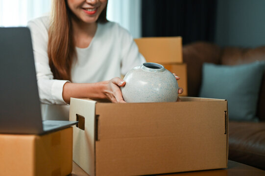 Woman online shop owner packing her goods into a parcel box. cropped image