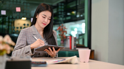 Elegant young-adult Asian businesswoman remote working in the coffee shop