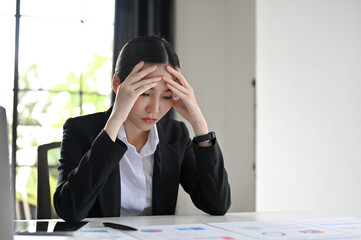 Young Asian businesswoman thoughtful and serious, pensively thinking about her financial plan