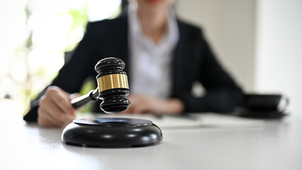 Fototapeta na wymiar Female lawyer with a judge gavel on the desk. Selective focus on judge gavel.