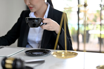 Fototapeta na wymiar Professional Asian female lawyer working in her office, sipping a morning coffee