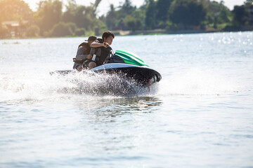 Fototapeta na wymiar Asian teenager on jet ski with trainer. Teen age boy skiing on wave runner. Young man on personal watercraft in tropical sea. Jet ski training. Sport and ocean activity on beach holiday.