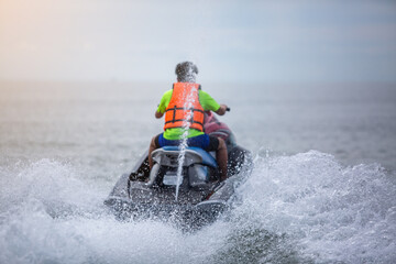 Blurry back view of teenager on jet ski. Teen age boy skiing on wave runner. Young man on personal...