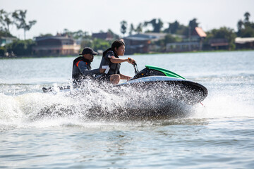 Asian teenager on jet ski with trainer. Teen age boy skiing on wave runner. Young man on personal...