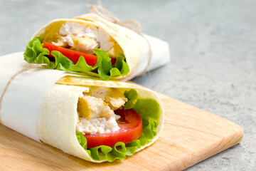 shawarma with chicken, tomatoes, sauce and lettuce on a wooden board. close-up
