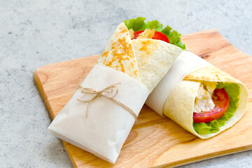 shawarma with chicken, tomatoes, sauce and lettuce on a wooden board. close-up