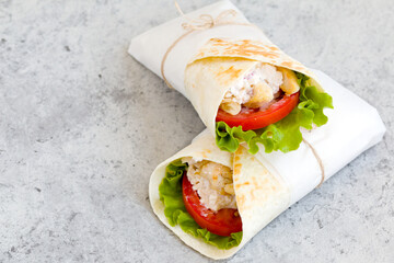 shawarma with chicken, tomatoes, sauce and lettuce on a gray background. close-up, copy space