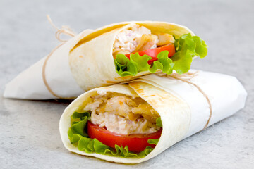 shawarma with chicken, tomatoes, sauce and lettuce on a gray background. close-up