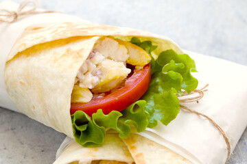 shawarma with chicken, tomatoes, sauce and lettuce on a gray background. close-up