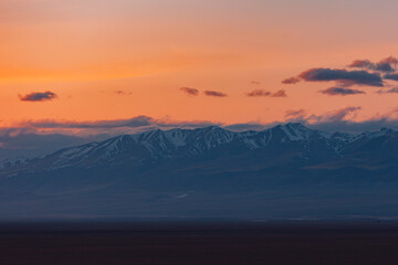 Red sunset with clouds in the Altai Mountains North Chuysky ridge, peaks with snow cover.