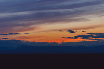 Fototapeta na wymiar Red sunset with clouds in the Altai Mountains North Chuysky ridge, peaks with snow cover.