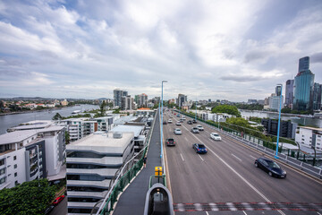 Brisbane city skyline viewed from the top of Story Bridge at sunset with glowing river and urban skyscrapers