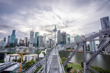 Brisbane city skyline viewed from the top of Story Bridge at sunset with glowing river and urban skyscrapers