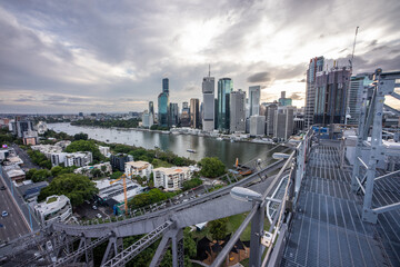 Brisbane city skyline viewed from the top of Story Bridge at sunset with glowing river and urban skyscrapers