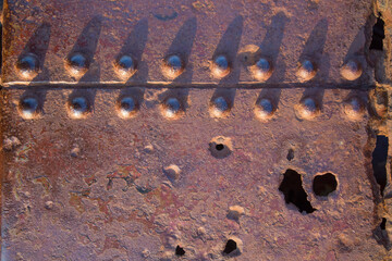 Rusty metal background or texture with large rivets and shadows