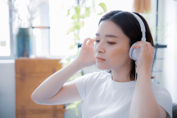 部屋でイヤホンで音楽を聴く日本人女性
