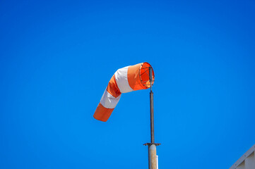 orange and white windsock on blue sky