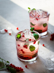 Cocktail with white rum, limoncello, currant berries and mint on a white concrete background