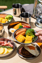 アウトドアのキャンプで食事をしている男性の手と料理