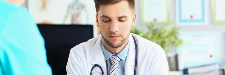 Young intern man in uniform and stethoscope, work meeting in doctor office