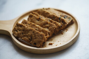 Healthy snack whole grains cookie crackers on a wooden plate white marble background rectangular shape closeup view