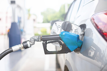 Hand of refueling worker are filling fuel to car in Petrol station. Focus on fuel nozzle and blur...