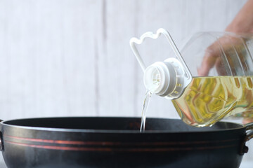 detail shot of Pouring vegetable oil into frying pan.