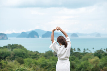 Fototapeta na wymiar happy woman in bathrobe stretching after waking up and enjoy Ocean view, Tourist relaxing in tropical resort. summer travel, holiday and vacation concept