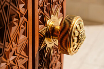 Round door handle with ornament. Antique handle on the background of a wooden door.